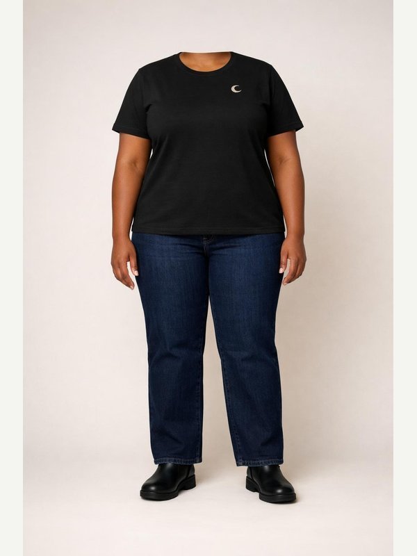 Witch A — AI-generated adult in black tee, blue jeans, black ankle boots and a tiny crescent brooch.