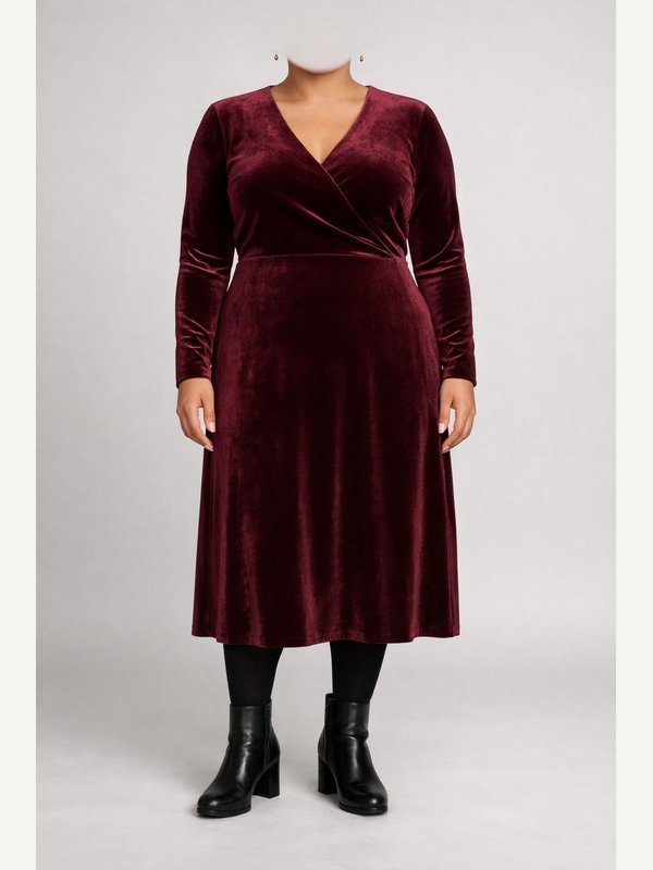 Adult woman in a deep burgundy velvet long-sleeve midi dress, black opaque tights, black heeled ankle boots and small gold earrings.